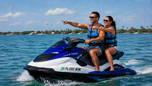 A male and female couple on a jet ski pointing at a dolphin in the distance.