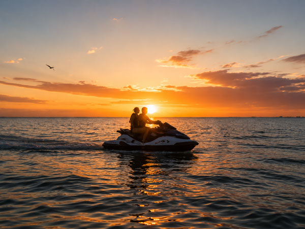 A male and female couple sitting on a jet ski by Manasota Key at sunset.